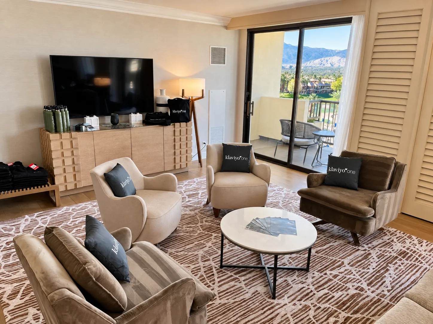 A resort suite set as a lounge, armchairs around a low table and a balcony looking out to the mountains