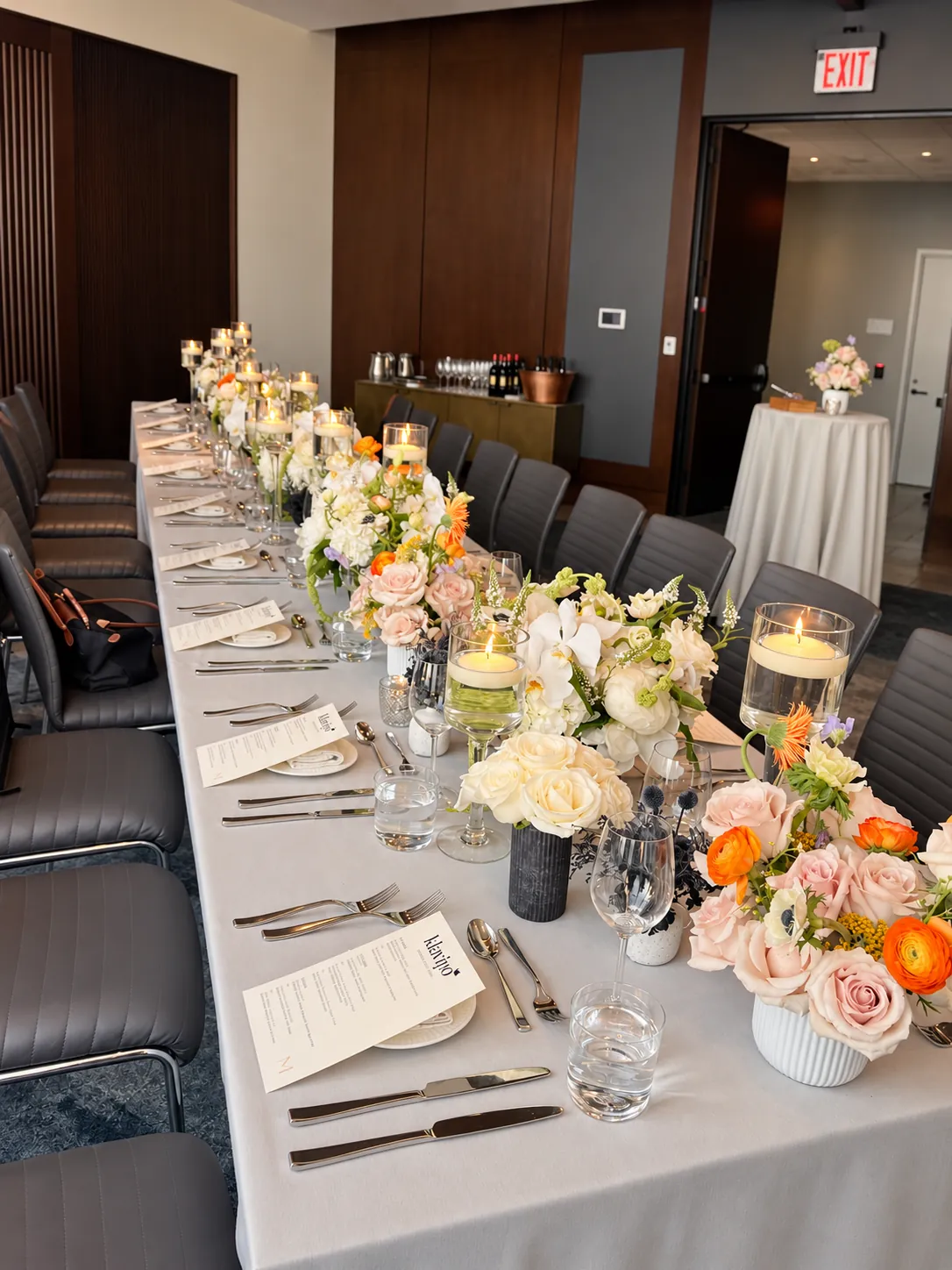 A long dinner table dressed with low florals and floating candles before guests arrive
