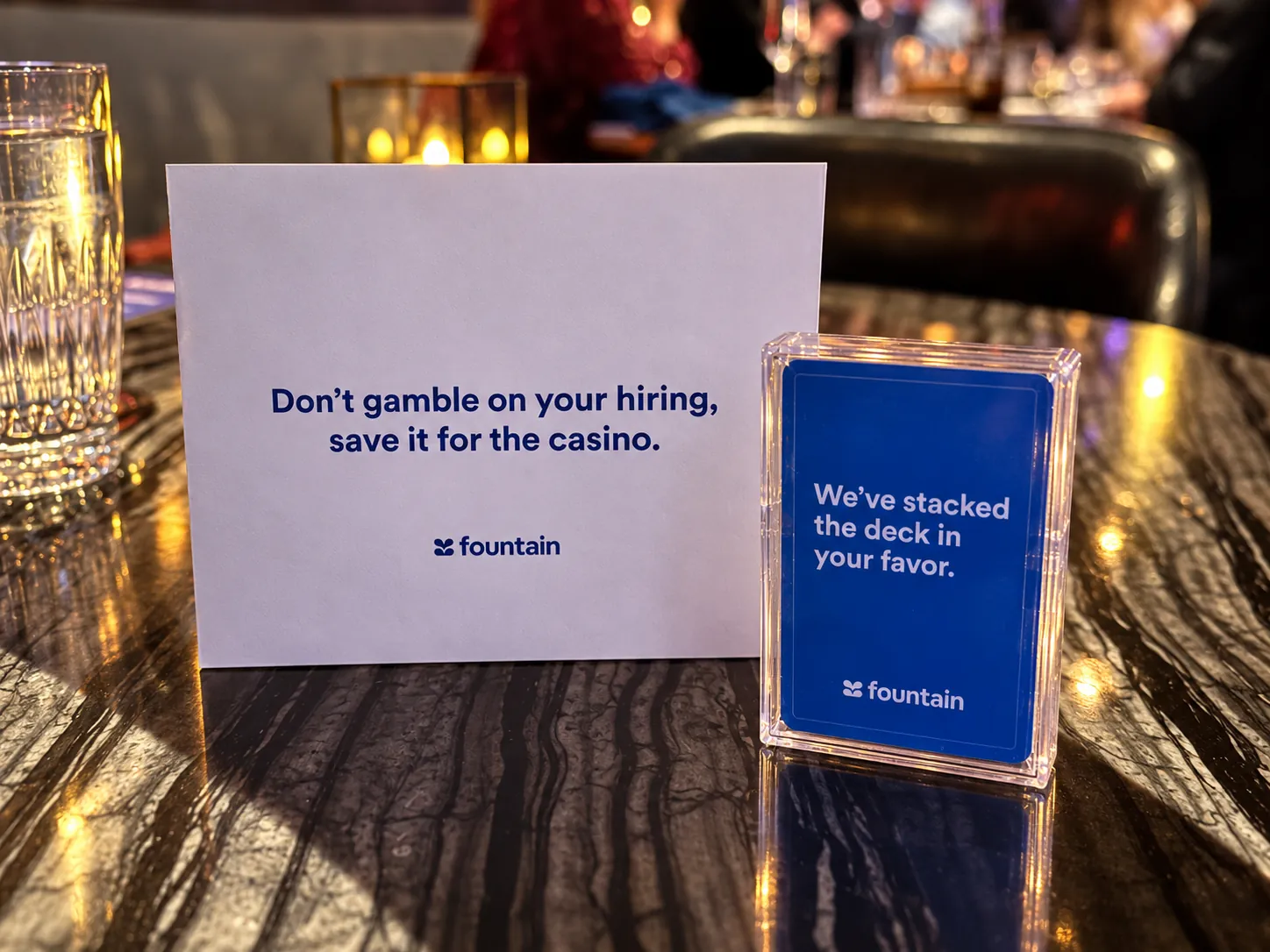 A printed table card reading 'Don't gamble on your hiring, save it for the casino' beside a boxed deck of playing cards